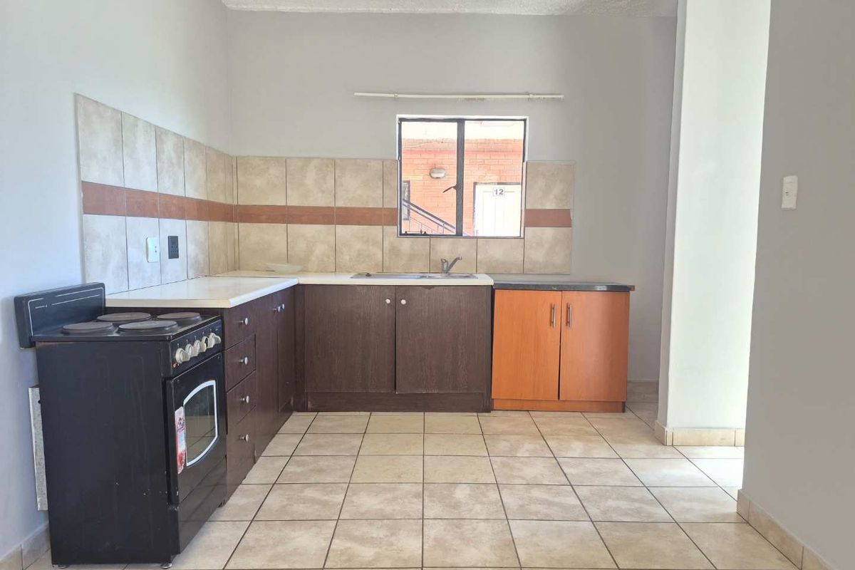 A functional kitchen featuring tiled flooring, a tiled backsplash, built-in cabinetry, and a stainless steel sink, offering a clean and practical layout.