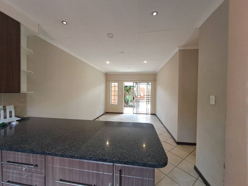 Open plan living area featuring tiled floors, recessed lighting, and a kitchen with granite countertops, leading out to a private outdoor space.