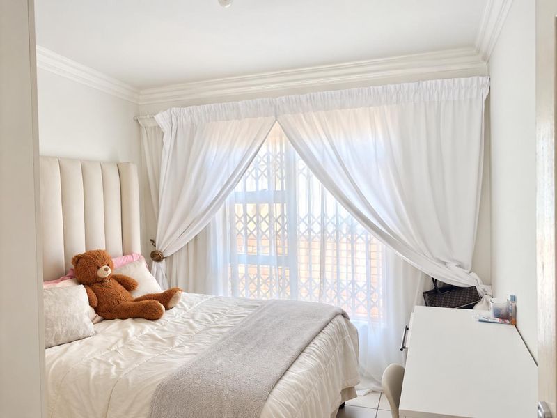 A bright and well-maintained bedroom featuring crown molding and a window fitted with a security gate.