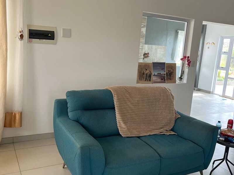 A living area featuring tiled flooring, an internal window looking through to an adjacent space, and a wall-mounted electrical distribution board.
