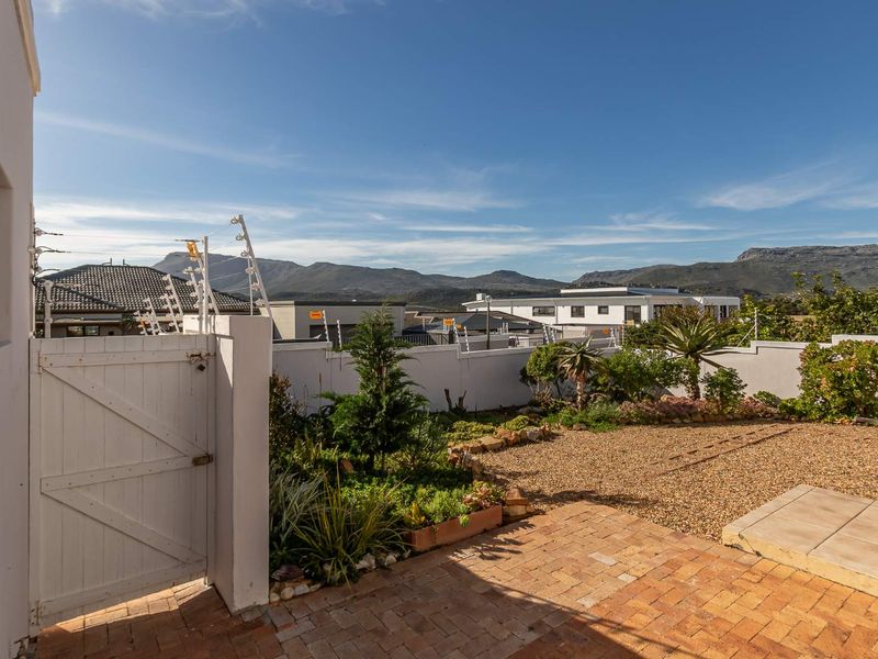 A low-maintenance garden featuring brick paving, gravel landscaping, and a secure perimeter wall with electric fencing, offering scenic mountain views.