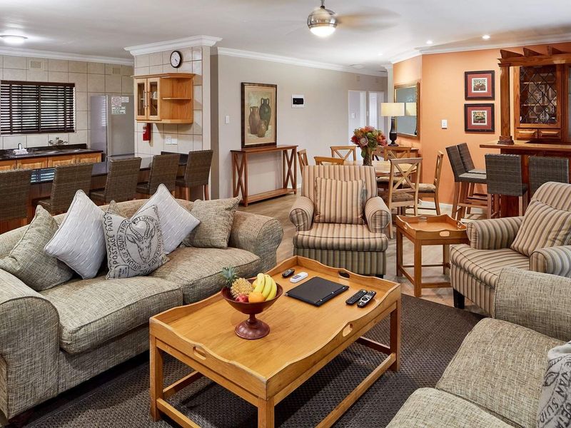 Spacious open-plan living area featuring a kitchen with island, dining space, and a built-in bar, finished with neutral tones and recessed lighting.