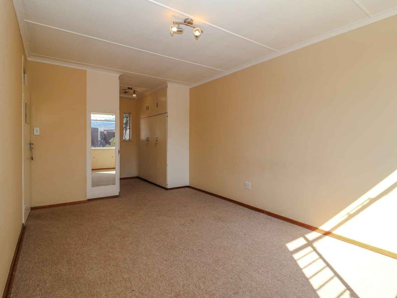 A vacant bedroom featuring neutral wall paint, carpeted flooring, and built-in storage cupboards.