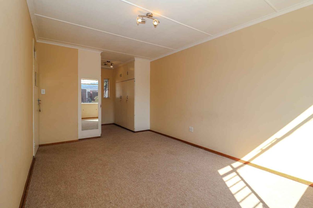 A vacant bedroom featuring neutral wall paint, carpeted flooring, and built-in storage cupboards.