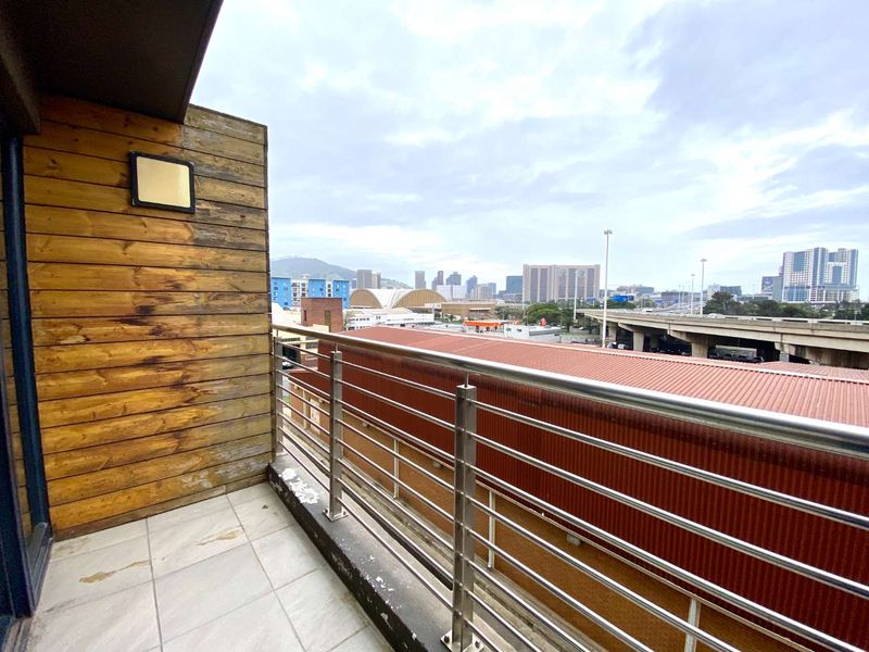 A balcony featuring tiled flooring, a stainless steel balustrade, and timber wall cladding, offering an elevated urban city view.