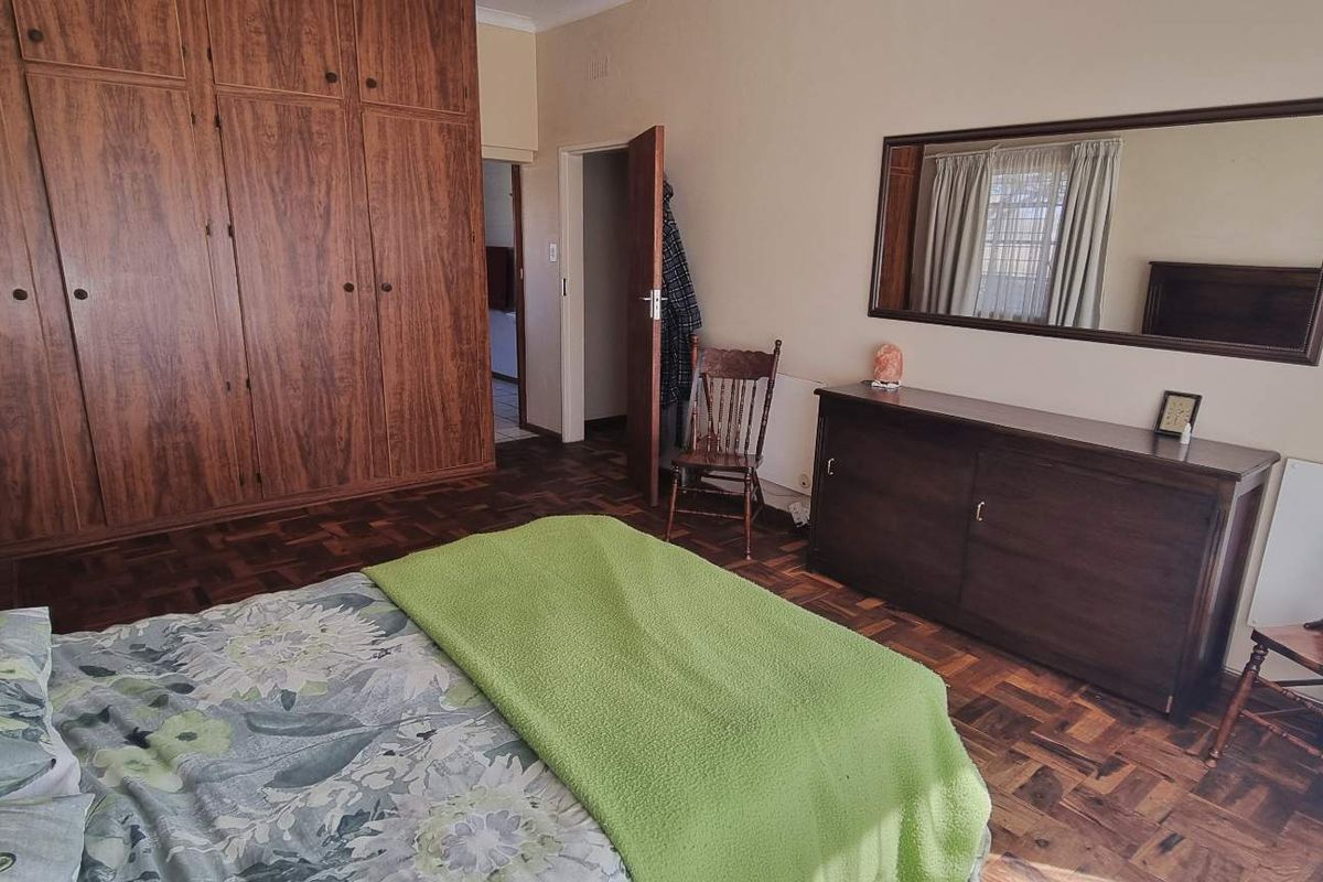 A bedroom featuring classic parquet flooring and extensive built-in wooden cabinetry, offering ample storage space.