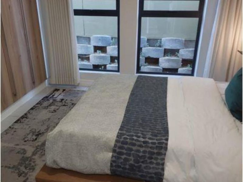 A modern bedroom featuring built-in cupboards, tiled flooring, and large windows providing natural light.