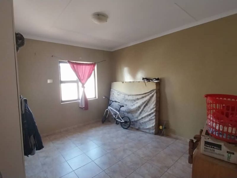 A bedroom featuring tiled flooring and a window with natural light, providing a functional space ready for personalization.