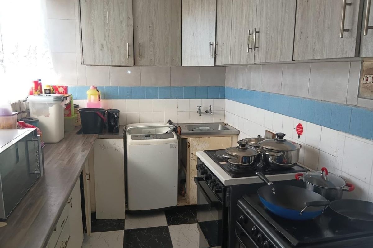A functional kitchen featuring wood-look cabinetry, tiled backsplash, and a freestanding stove, requiring some cosmetic updates to improve its overall condition.