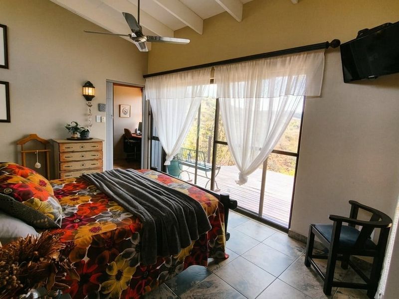 A bedroom featuring tiled floors, exposed ceiling rafters, and a sliding glass door providing access to an outdoor deck area.
