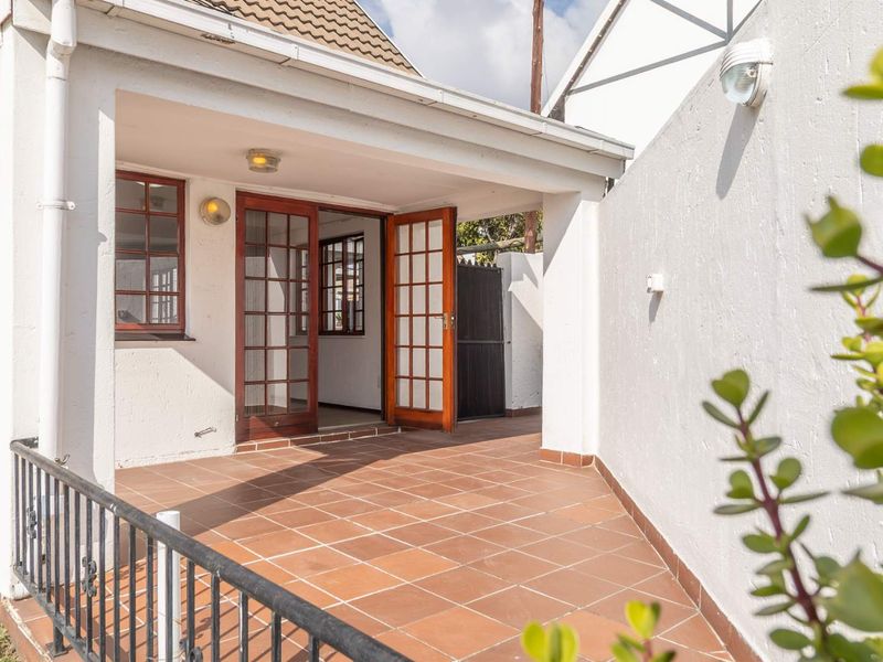 A covered patio area featuring tiled flooring, metal railings, and wooden french doors leading into the home.