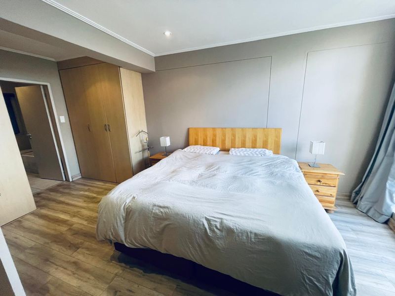 A well-maintained bedroom featuring laminate flooring, built-in wardrobes, and neutral wall finishes, offering a clean and functional living space.