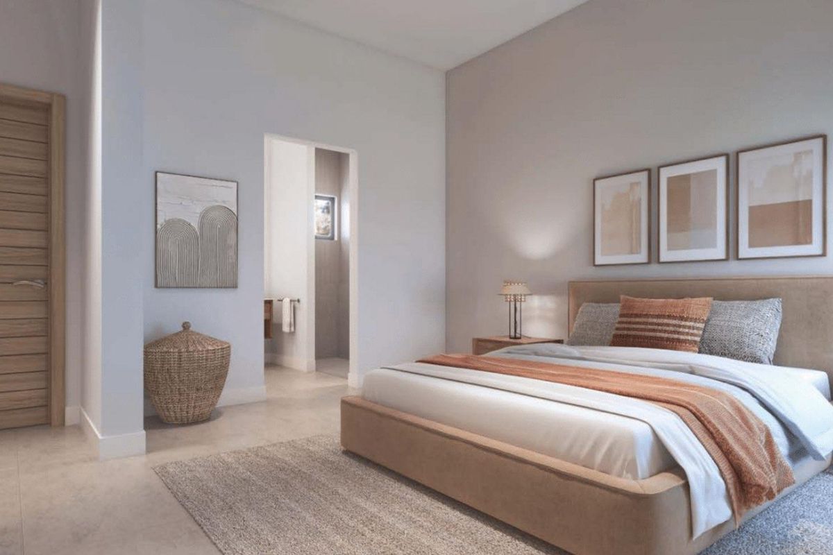 A modern, well-lit bedroom featuring neutral tones, clean architectural lines, and an adjoining en-suite bathroom.