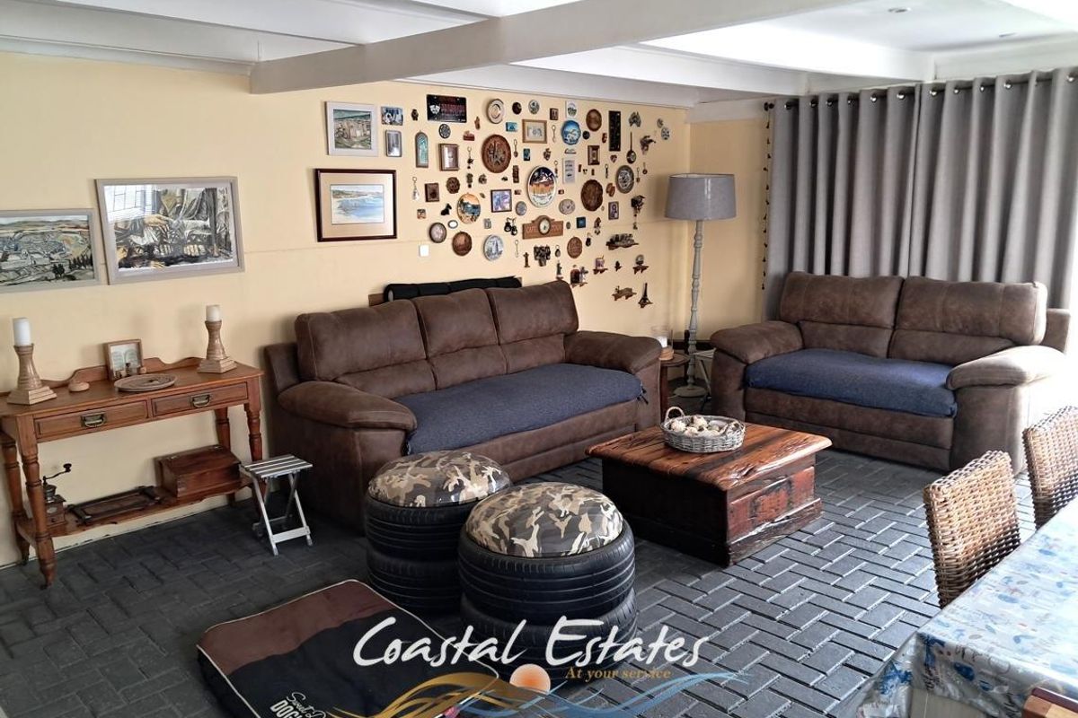 A spacious living area featuring exposed ceiling beams and durable brick flooring, creating a rustic and comfortable atmosphere.