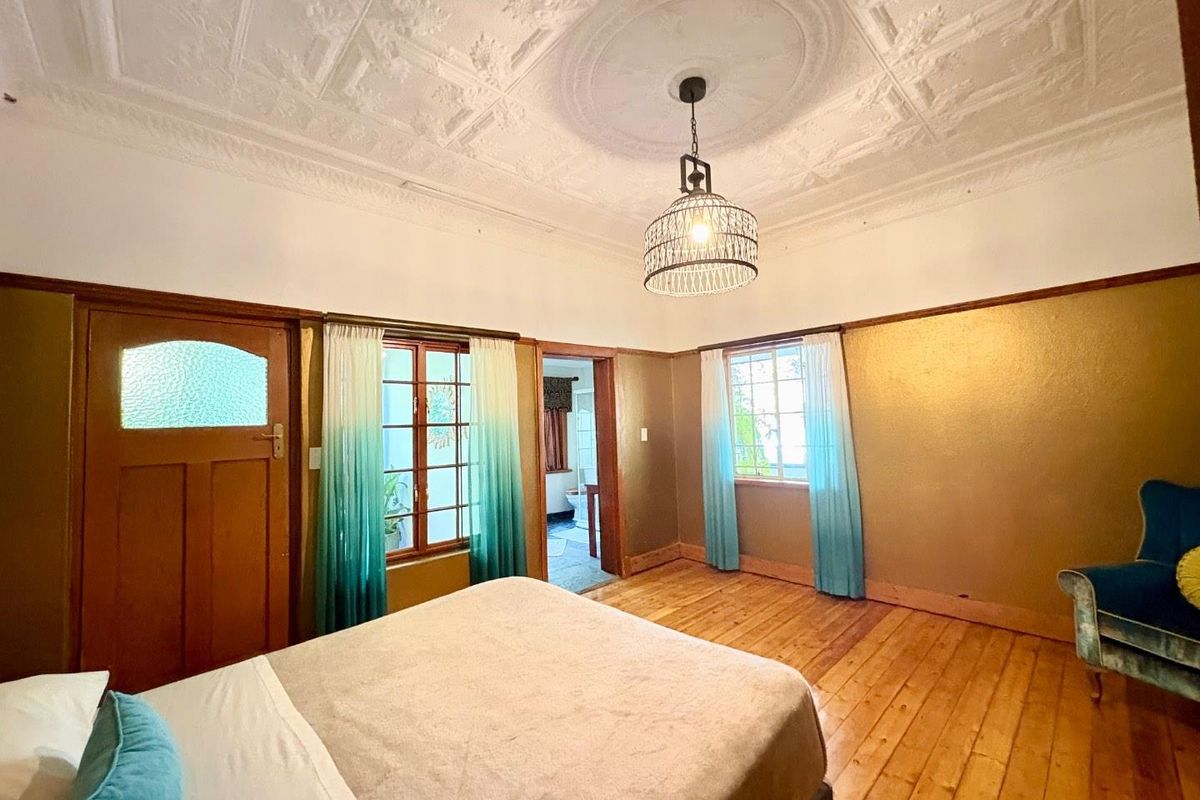 Spacious bedroom featuring original pressed metal ceilings, timber flooring, and large windows allowing for natural light.