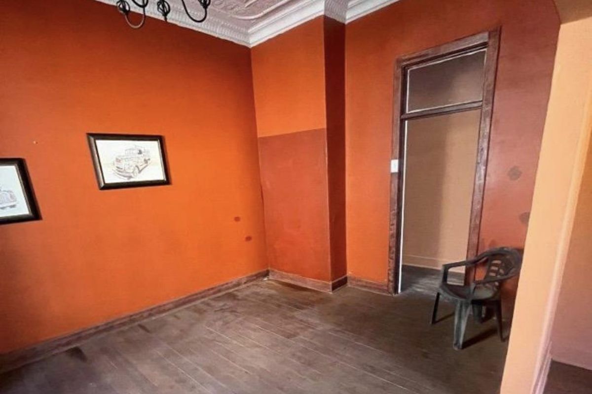 A vacant room featuring original timber flooring, decorative ceiling cornices, and a doorway leading to an adjacent space.