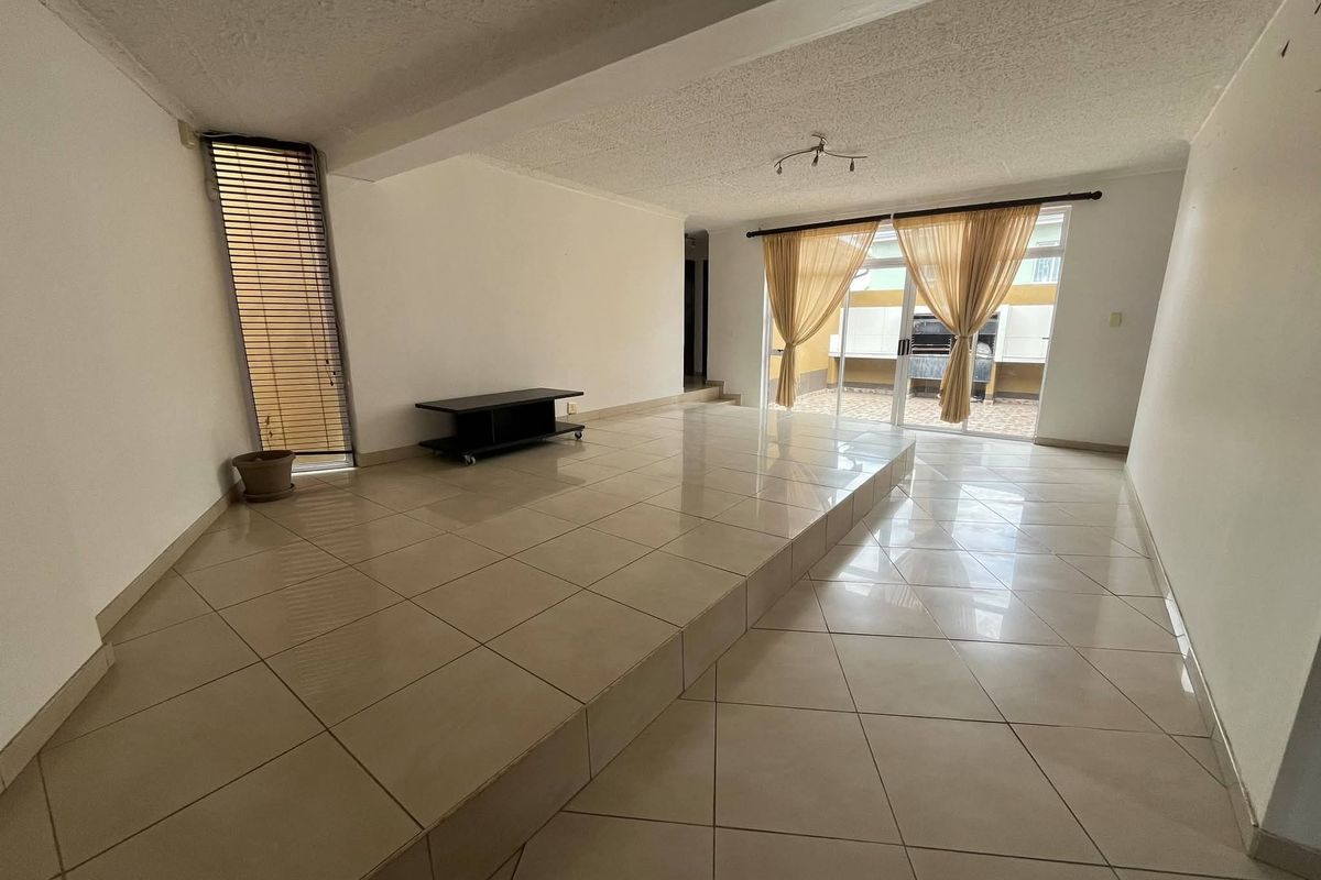 Spacious living area featuring a unique raised tiled platform, textured ceiling, and sliding glass doors providing access to the outdoor patio area.