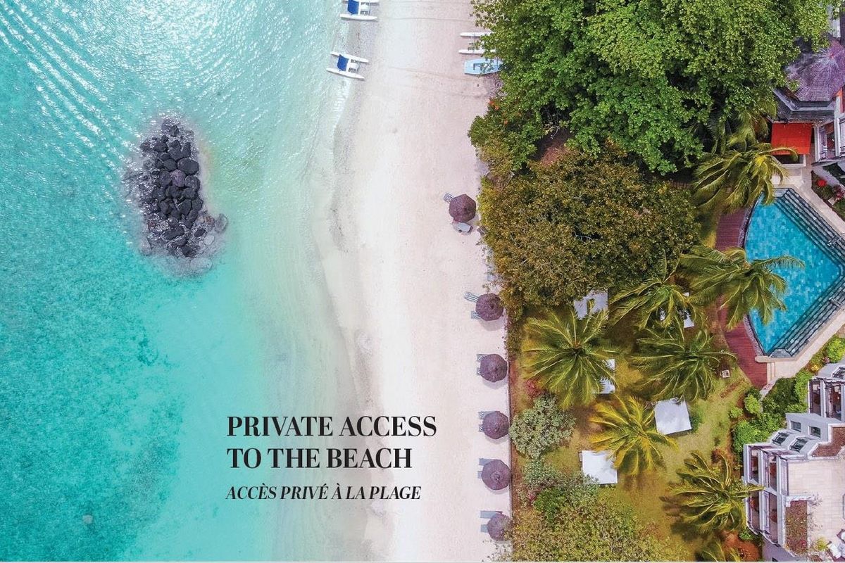 Aerial view of the property grounds featuring a swimming pool, landscaped gardens, and direct private access to the sandy beach and ocean.