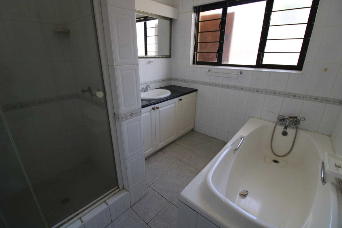 A functional bathroom featuring a separate shower enclosure, a built-in bathtub, and a vanity cabinet with a countertop basin.