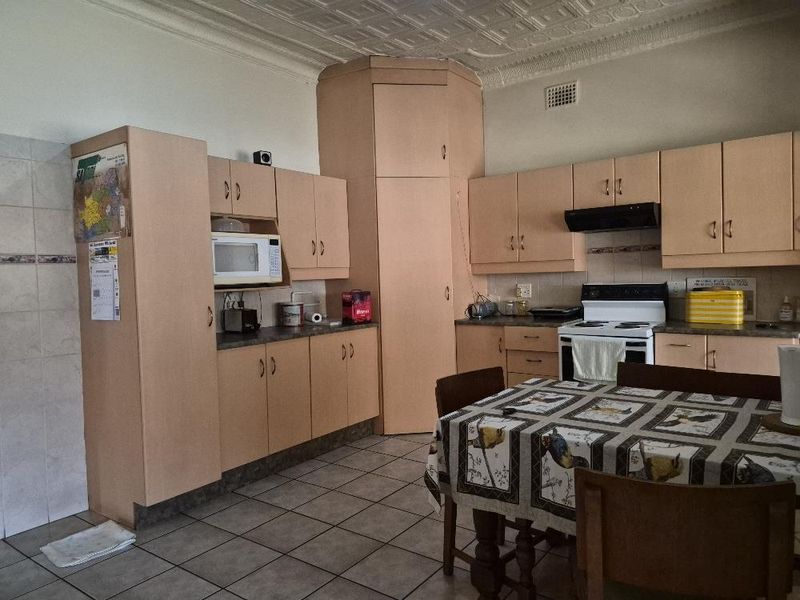 A functional kitchen featuring laminate cabinetry, tiled flooring, a tiled backsplash, and a classic pressed metal ceiling.