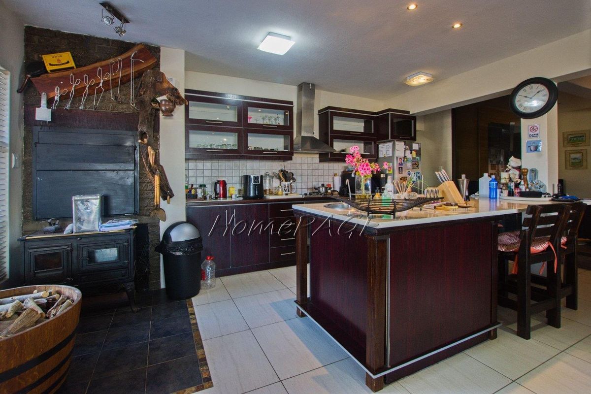 A functional kitchen featuring dark wood cabinetry, a central island with stone countertops, and an integrated fireplace, offering a warm and practical cooking space.