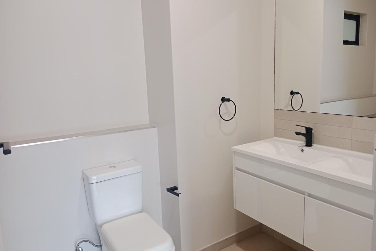 Modern bathroom featuring a wall-mounted vanity with a sleek black mixer tap, tiled splashback, and a clean, minimalist design.