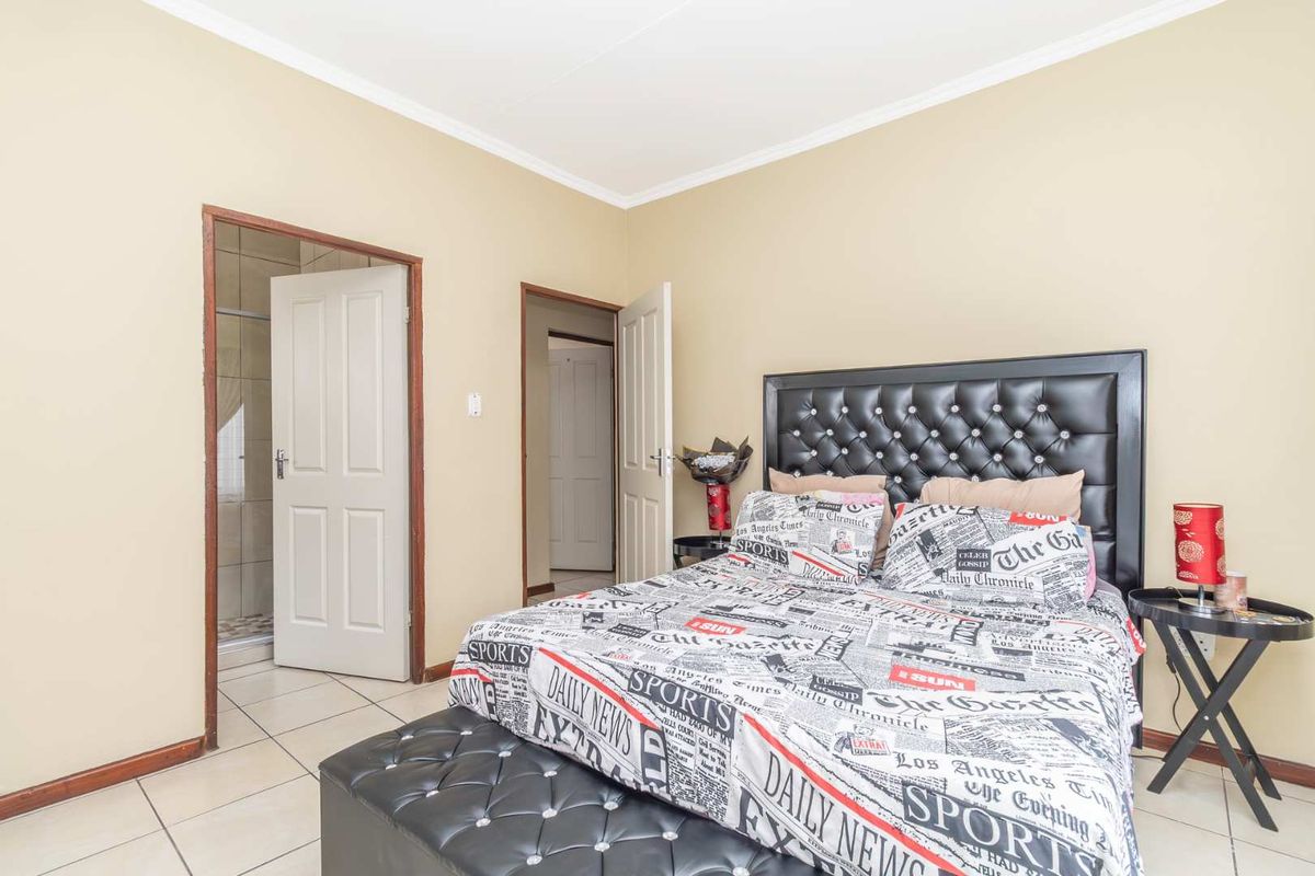 A bedroom featuring tiled flooring, neutral wall paint, and an en-suite bathroom access point.