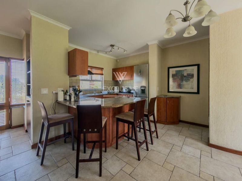 A functional kitchen featuring wooden cabinetry, granite countertops, a breakfast bar, and tiled flooring, offering a practical layout for daily use.