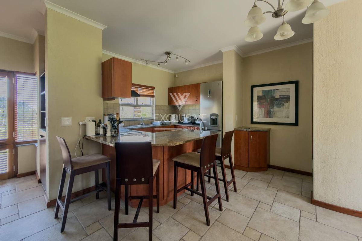 A functional kitchen featuring wooden cabinetry, granite countertops, a breakfast bar, and tiled flooring, offering a practical layout for daily use.