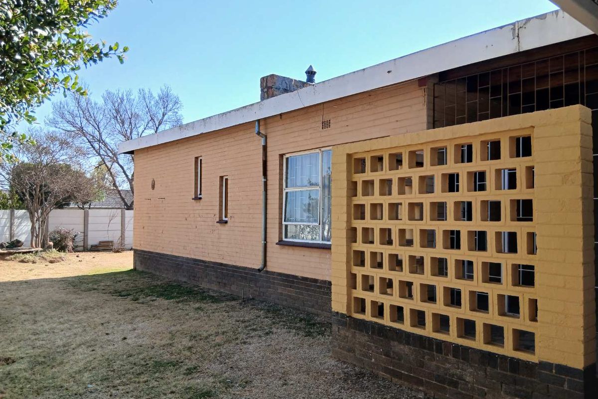 Rear exterior view of the house featuring a brick facade, a decorative breeze block screen wall, and a chimney stack.