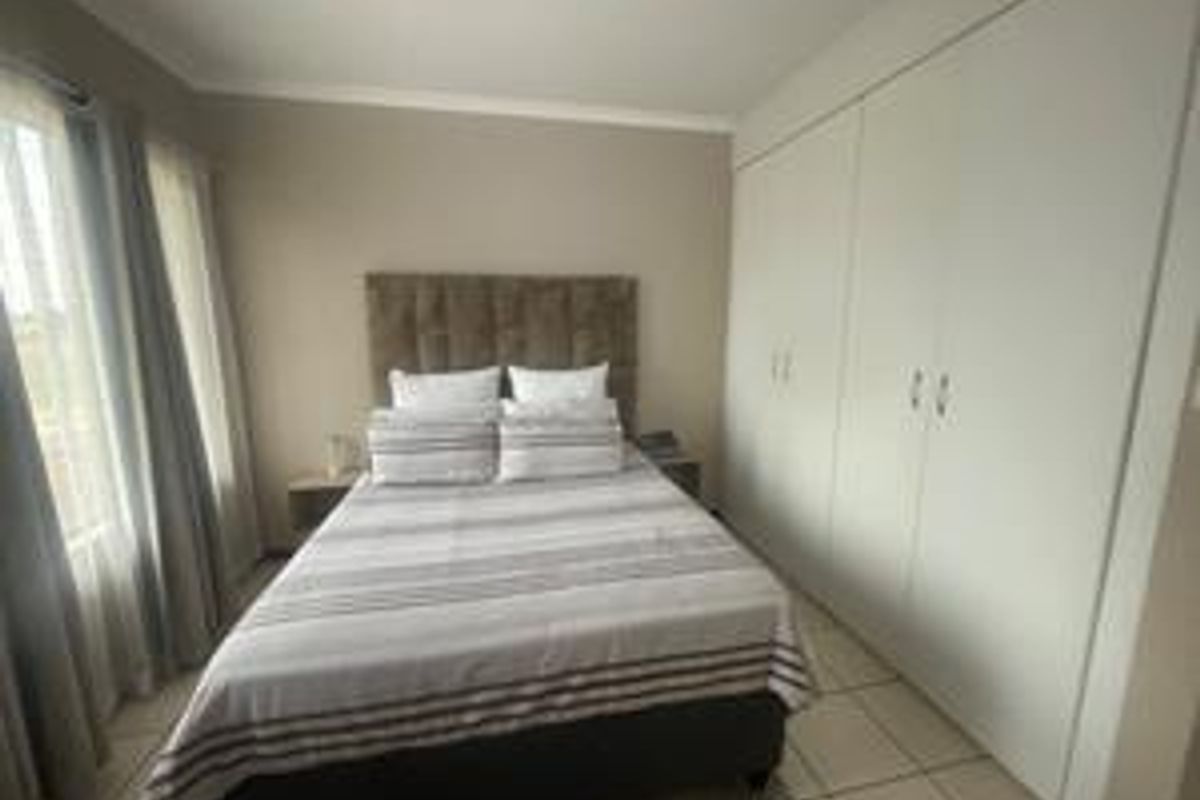 A well-maintained bedroom featuring neutral walls, tiled flooring, and ample built-in cupboard storage.