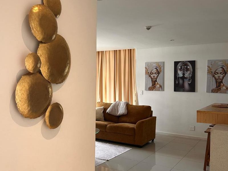 An open-plan living area featuring polished floor tiles, recessed lighting, and a breakfast bar, creating a bright and connected living space.