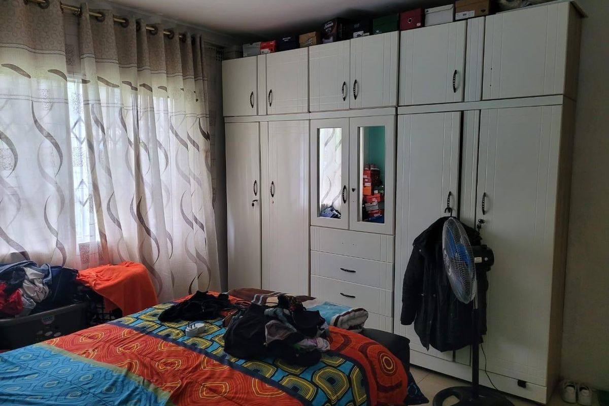 A bedroom featuring extensive white built-in cupboards with integrated storage and recessed ceiling lighting.