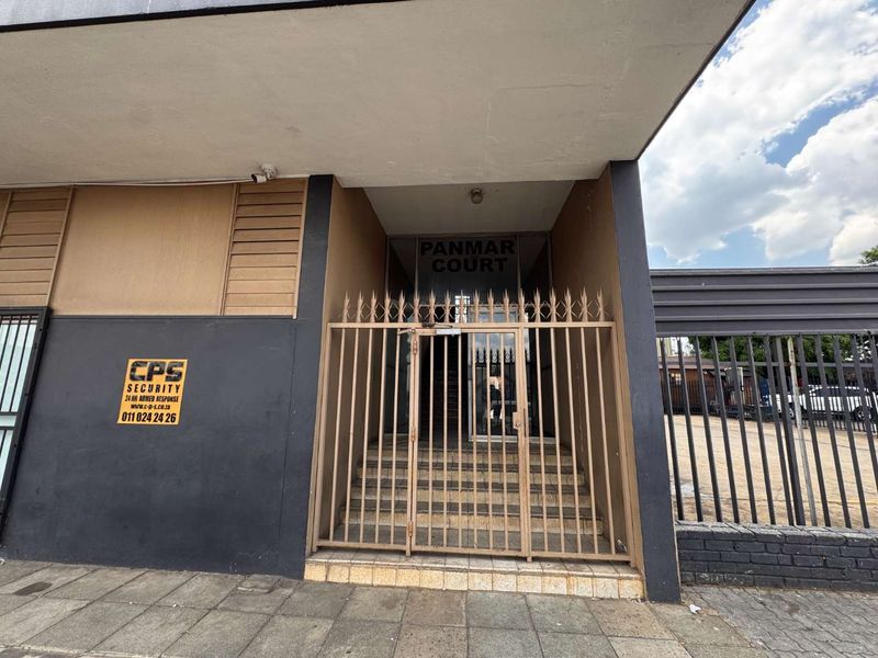 Front entrance of Panmar Court featuring a secure metal gate, tiled steps, and exterior security signage.