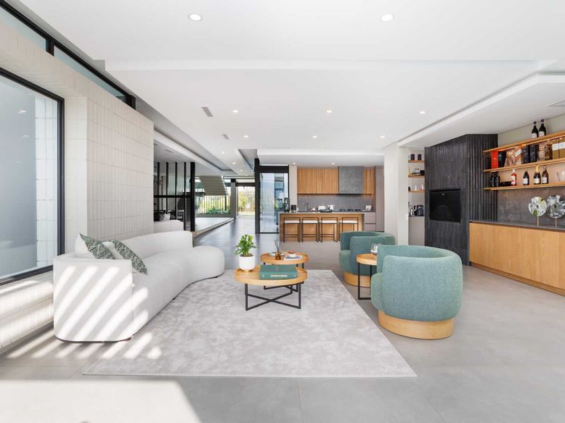 Spacious open-plan living area featuring a modern kitchen with wood cabinetry, integrated appliances, and seamless flow to the lounge and dining spaces.