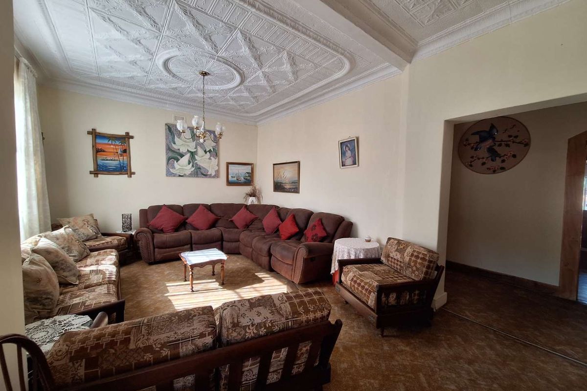 Spacious living room featuring a decorative pressed metal ceiling, carpeted flooring, and an open-plan layout connecting to adjacent living areas.