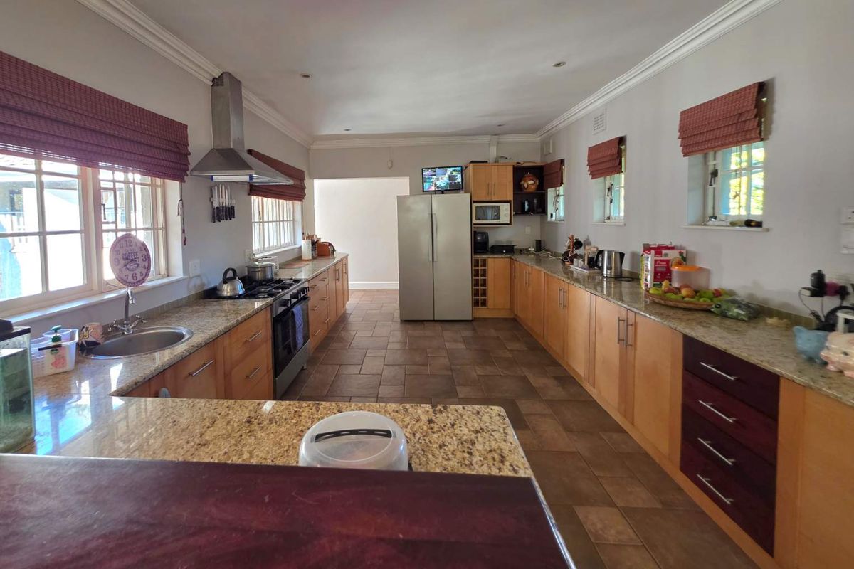 Spacious kitchen featuring granite countertops, wooden cabinetry, a built-in oven with extractor fan, and tiled flooring.
