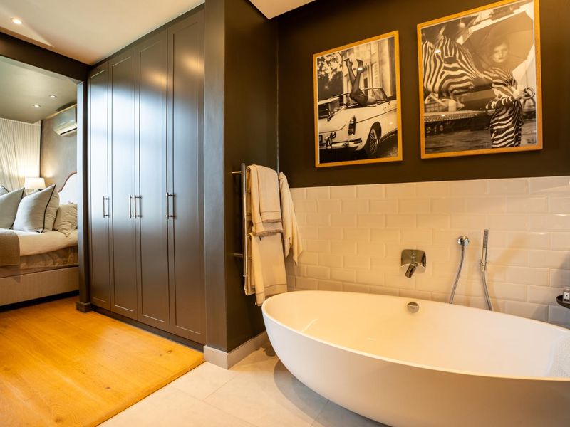 Modern bathroom featuring a sleek freestanding bathtub, subway tile splashback, and extensive built-in cabinetry, seamlessly connected to the adjacent bedroom area.