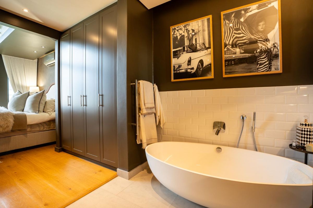 Modern bathroom featuring a sleek freestanding bathtub, subway tile splashback, and extensive built-in cabinetry, seamlessly connected to the adjacent bedroom area.