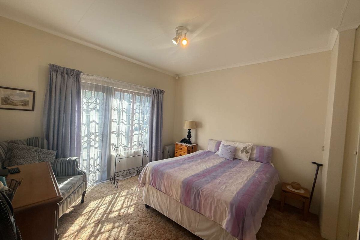 A bedroom featuring carpeted flooring and a sliding glass door with security gate, providing access to the exterior.