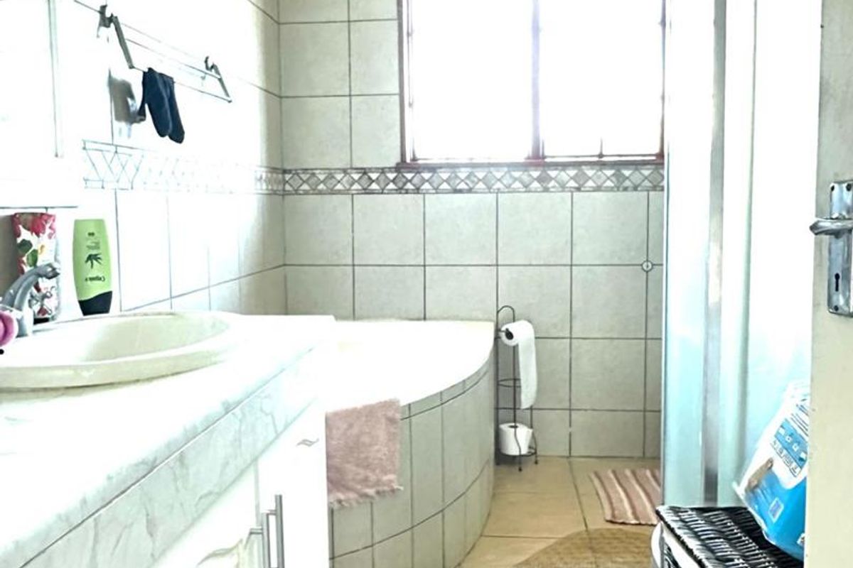 A functional bathroom featuring a built-in vanity, a corner bathtub, and a separate shower enclosure with tiled walls and flooring.