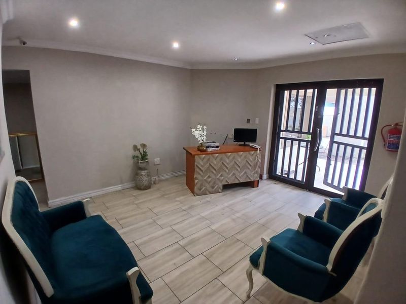A well-lit office or reception area featuring tiled flooring, recessed ceiling lights, and a secure glass door with a metal security gate.