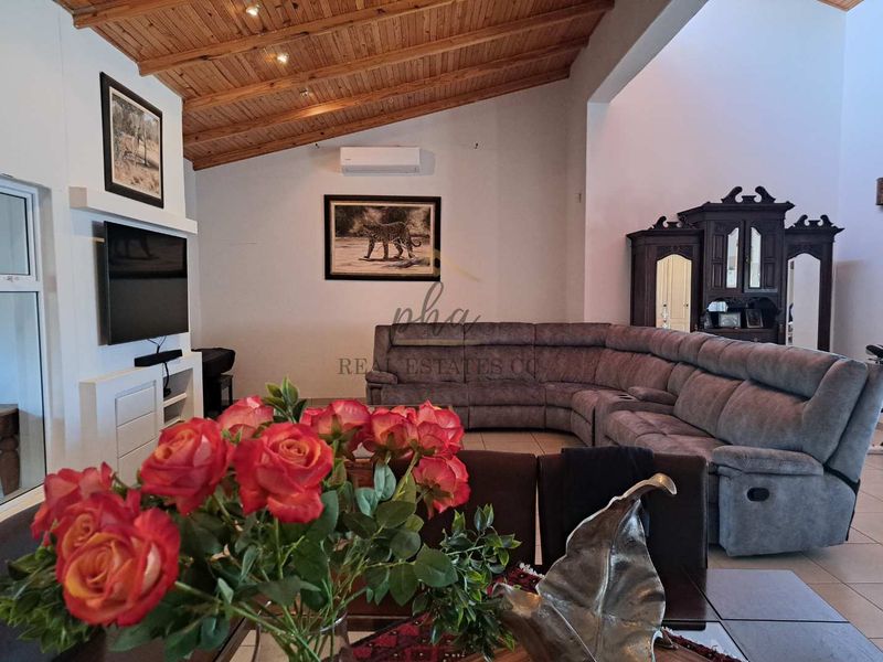 Spacious living room featuring a high exposed timber beam ceiling, tiled flooring, and a built-in media console with integrated air conditioning.