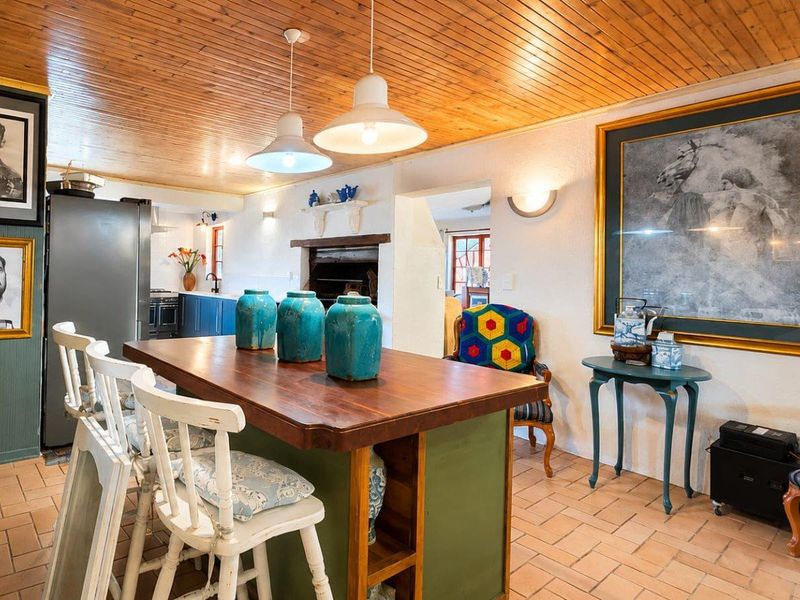 Open-plan kitchen and dining area featuring a timber-clad ceiling, terracotta flooring, and a central kitchen island with integrated cabinetry.