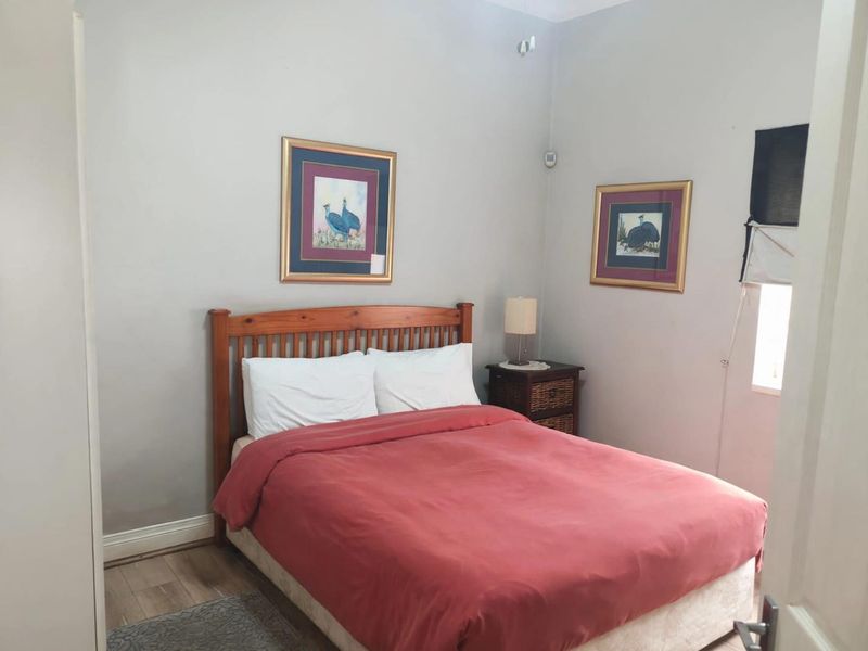 A functional bedroom featuring laminate flooring, neutral wall tones, and a window with a roller blind, providing a comfortable and well-maintained living space.
