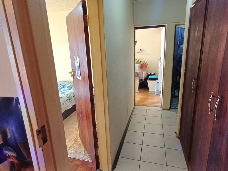 A functional hallway featuring tiled flooring and built-in wooden cupboards, providing access to adjacent rooms within the apartment.