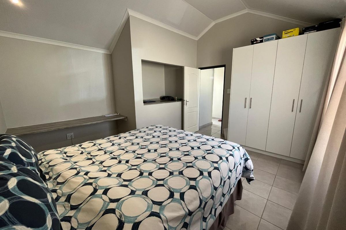 A well-maintained bedroom featuring vaulted ceilings, built-in white cabinetry, and tiled flooring, offering a clean and functional living space.