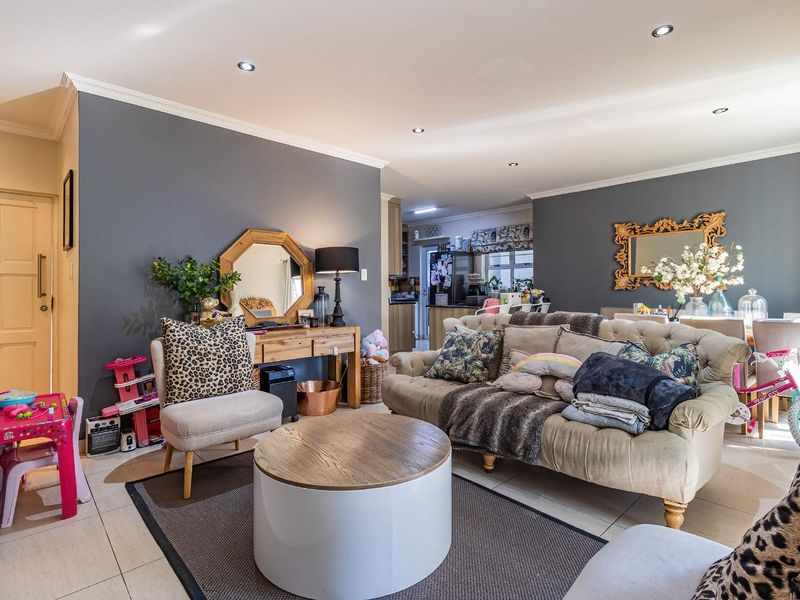 Spacious open-plan living area featuring tiled flooring, recessed downlighting, and neutral wall finishes, seamlessly connecting to the kitchen space.
