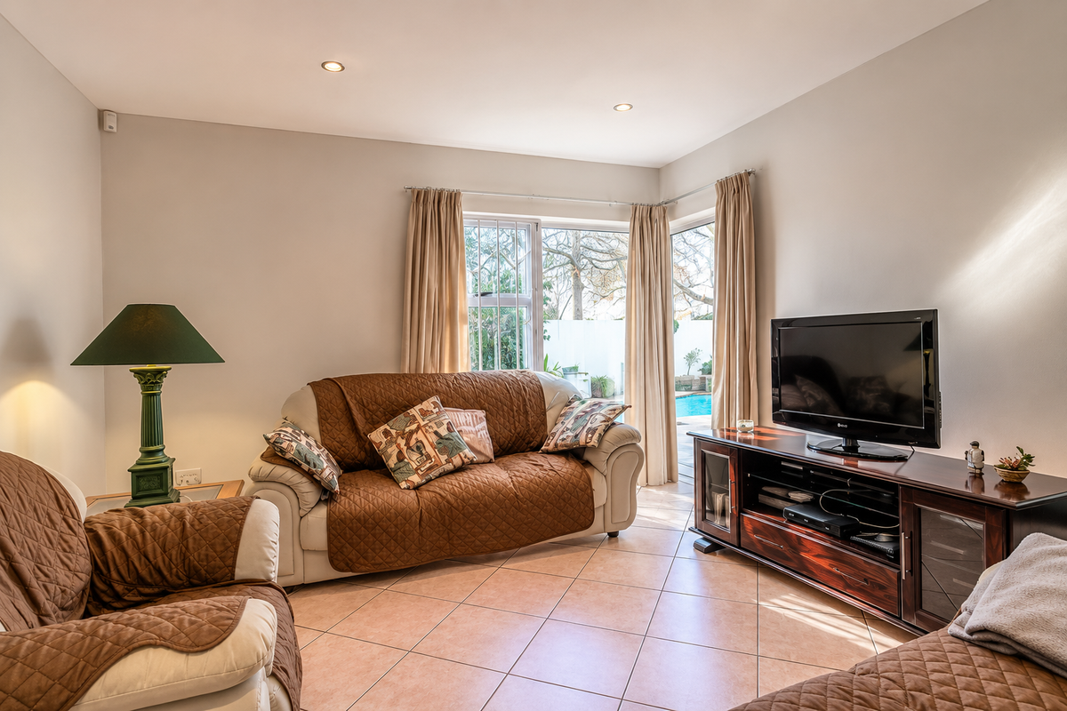 A comfortable living room featuring ceramic tile flooring, recessed lighting, and a sliding glass door providing direct access to the outdoor pool area.