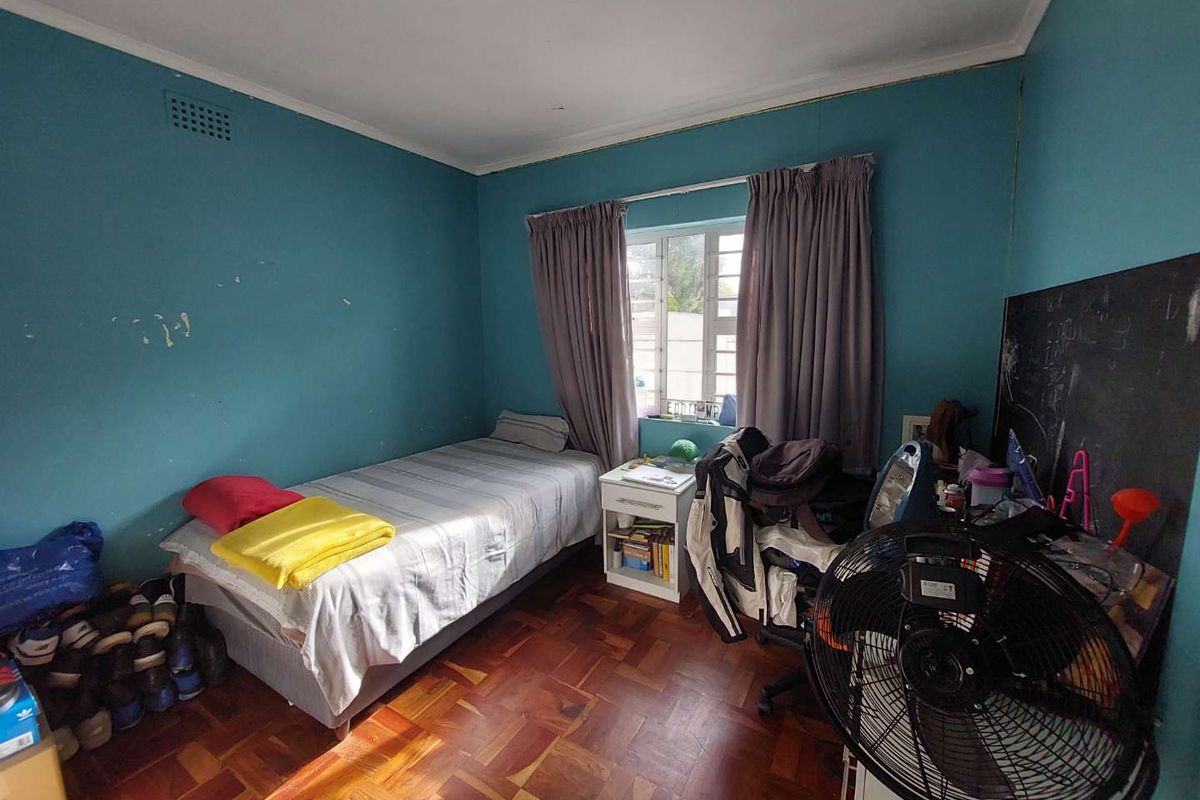 A bedroom featuring parquet flooring and a ceiling vent, currently requiring cosmetic updates to the wall finishes.